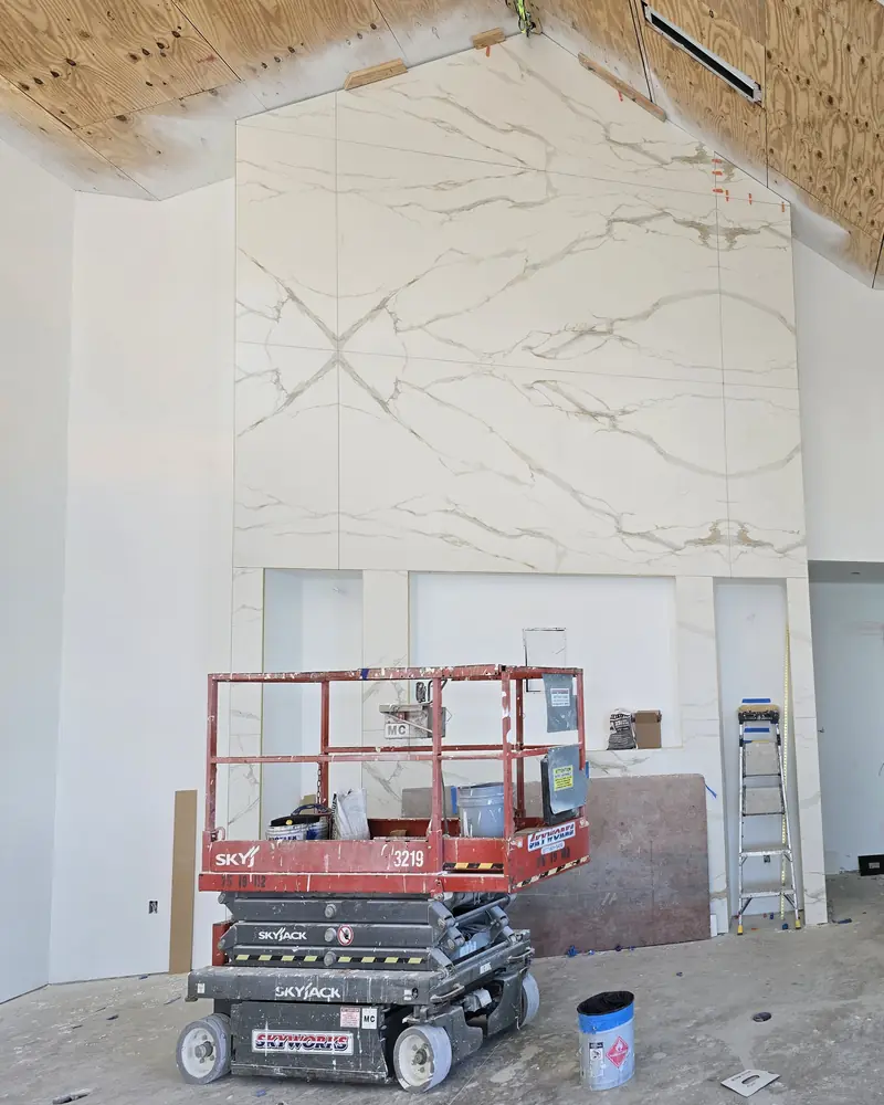 The fireplace wall in progress, with a scissor lift and a bare plywood ceiling